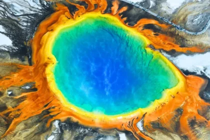 A vibrant aerial view of Thermal Pools at Yellowstone National Park, showcasing the delicate ecosystems threatened by tourists throwing coins.