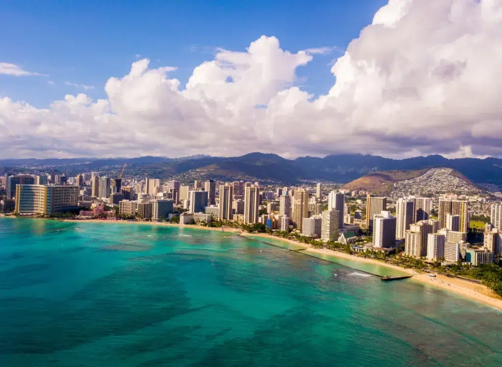 U.S. Cities with the Best Weather – A stunning aerial view of Honolulu, Hawaii, USA, featuring blue waters, a vibrant skyline, and lush mountains.