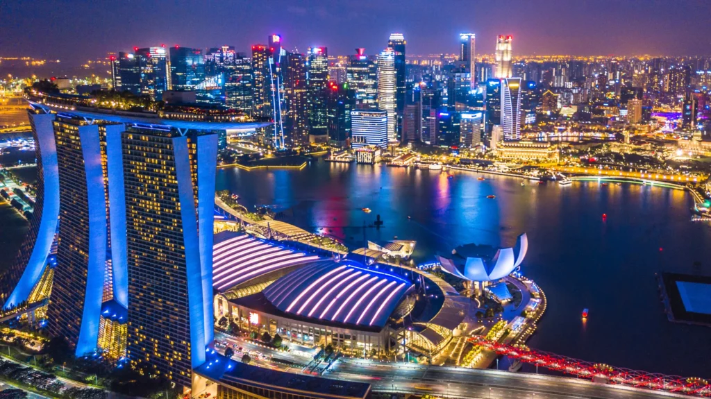 A stunning aerial night view of Singapore's Marina Bay Sands and skyline, showcasing its vibrant lights and modern architecture.